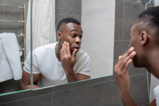 istock Dark-skinned young handsome man looking at himself in the mirror 1305580267