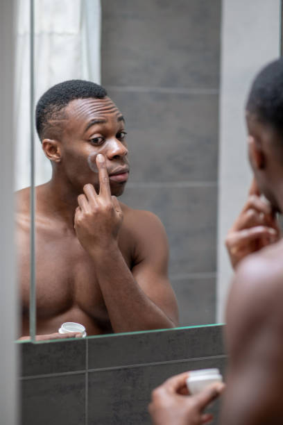istock African american short-haired guy applying some cream on his face 1305580276