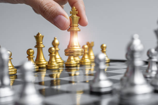 istock businessman hand moving gold Chess King figure and Checkmate opponent during chessboard competition. Strategy, Success, management, business planning, disruption and leadership concept 1305583850