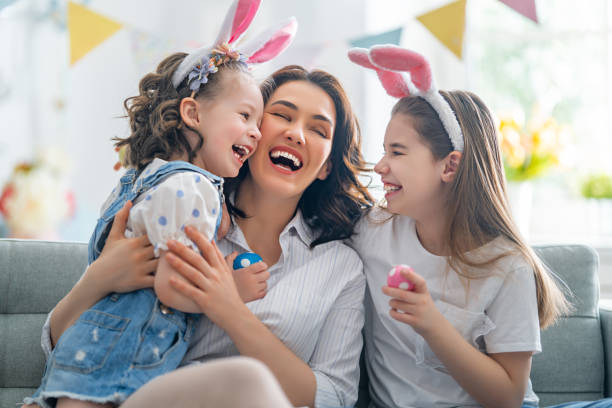 Family celebrating Easter. Happy holiday! Mother and her daughters with painting eggs. Family celebrating Easter. Cute little children girls are wearing bunny ears. easter egg photos stock pictures, royalty-free photos & images