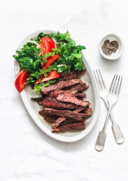 istock Beef steak and kale, tomato salad - delicious balanced diet lunch on a light background, top view 1305586970