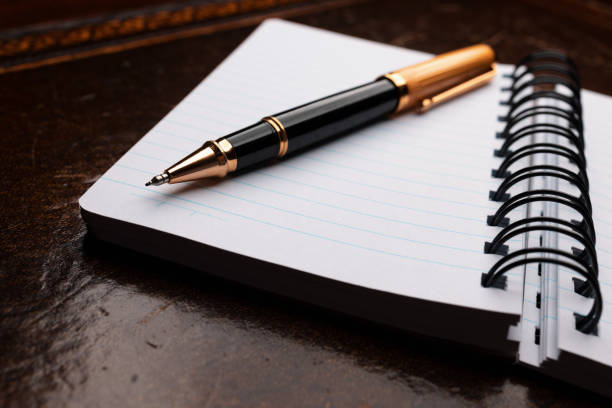 Opened notepad in a cage with an automatic plastic ballpoint pen close-up.