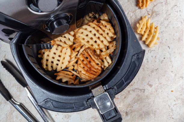 Air frying waffle potato fries at home stock photo