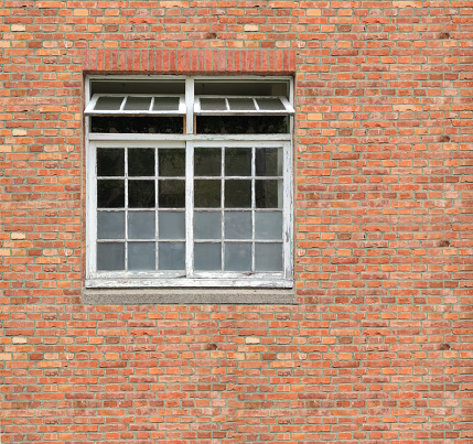 White painted wood arched window in a red brick wall