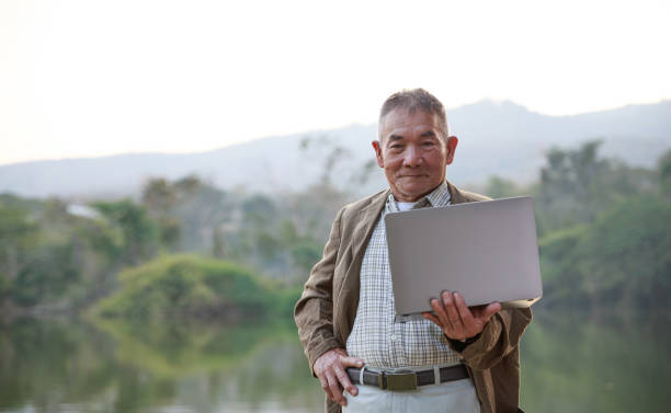 istock Asian old man using laptop in public park. 1305597804