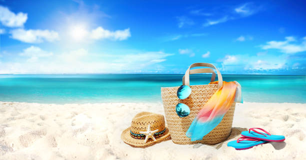 Concept summer holiday. Concept summer holiday. Accessories - bag, straw hat, sunglasses with palm tree reflection, pareo, flip-flops on sandy beach against ocean, blue sky, clouds and bright sun. Beautiful colorful image. beach bag stock pictures, royalty-free photos & images
