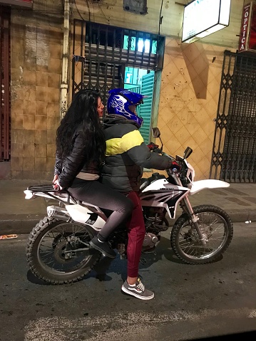La Paz Bolivia-May 2019: Bolivian husband and wife ride a motorcycle along the street of La Paz town