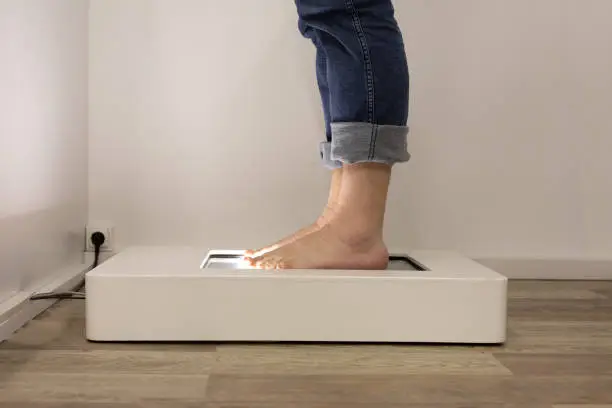 Foot scanning to determine exact size and feet form. Man using the electric device in a shoe store.