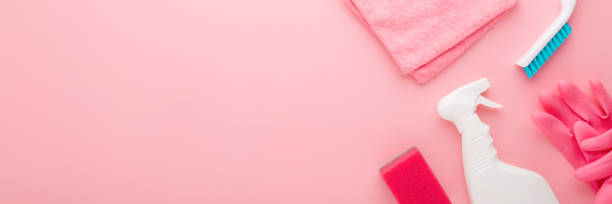 istock Simple cleaning set for different surfaces in kitchen, bathroom or other rooms. Spring regular cleanup. Light pastel pink background. Closeup. Top down view. Wide banner. Empty place for text or logo. 1305607703