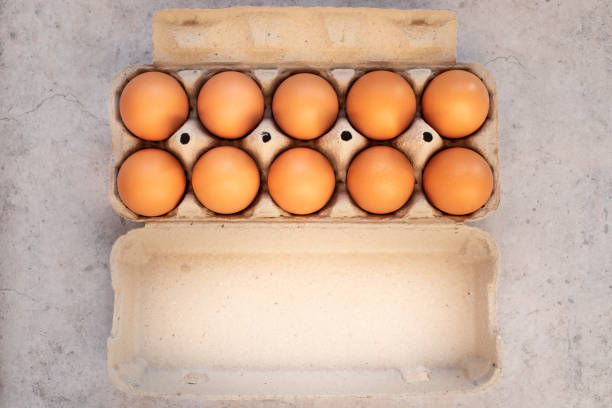 A dozen organic farms of fresh brown eggs in paper cardboard with eggs on a rustic background