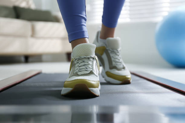 mujer entrenando en cinta de correr caminando en casa, primer plano - relleno ropa protectora deportiva fotografías e imágenes de stock