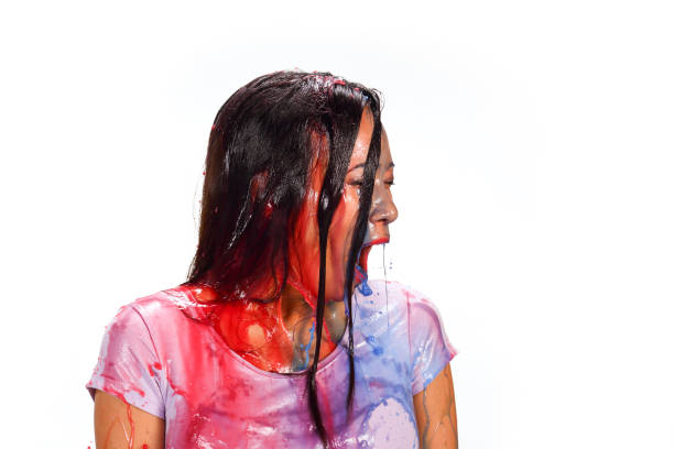 Asian woman being splashed with colored water. Red and blue. Surprise.