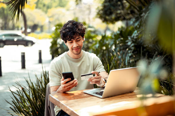 Young man shopping online Young man sitting at the cafe and paying online with credit card retail technology stock pictures, royalty-free photos & images