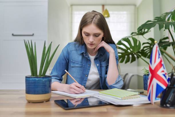istock UK learning English online. Female student remotely looking at webcam 1305616152