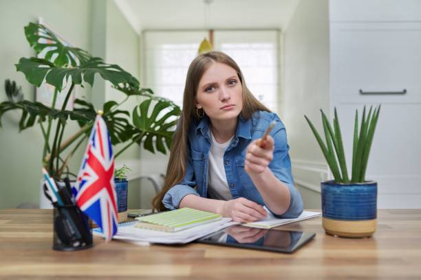 istock UK learning English online. Female student remotely looking at webcam 1305616159