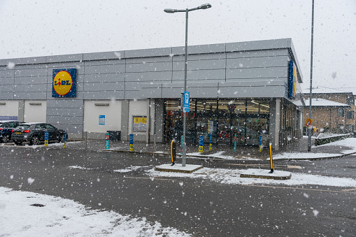 Lidl supermarket in a snow shower. This is in Huntingdon, Cambridgeshire, UK.