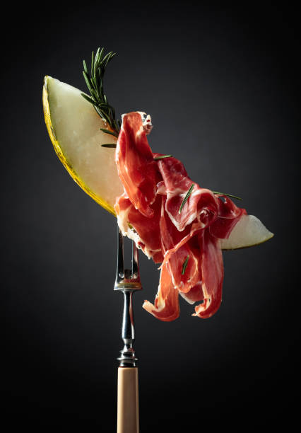 istock Melon with prosciutto and rosemary on a black background. 1305627549