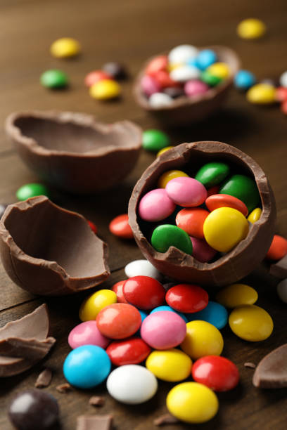 istock Broken chocolate eggs and colorful canzdies on wooden table, closeup 1305629110