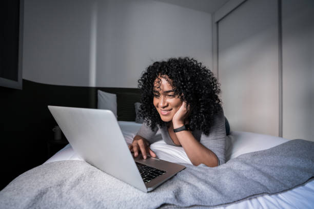 istock Woman using laptop lying on bed at home 1305630136