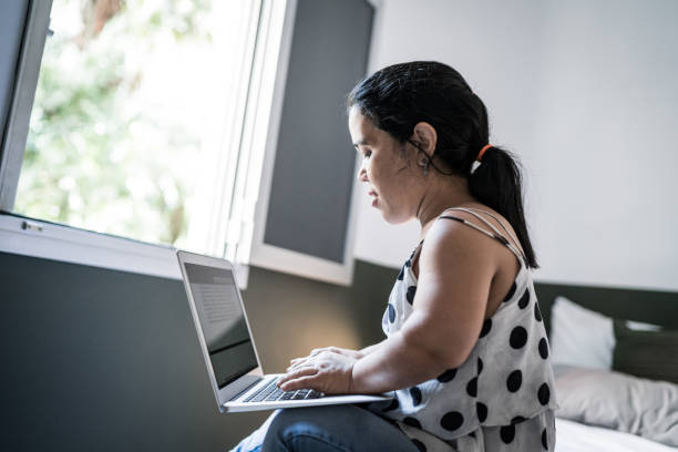 Dwarfism woman using laptop on bed at home Dwarfism woman using laptop on bed at home short stature stock pictures, royalty-free photos & images