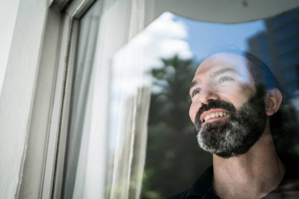 istock Mature man looking through window at home 1305630250