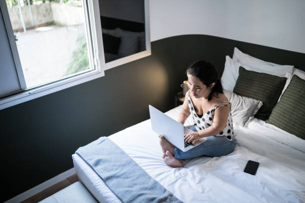 istock Dwarfism woman using laptop on bed at home 1305630363