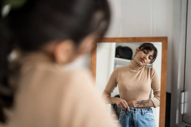 自宅で鏡の前で服を着ている若い女性 - 試着室 ストックフォトと画像