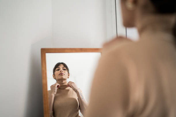 istock Young woman getting dressed in front of a mirror at home 1305630462