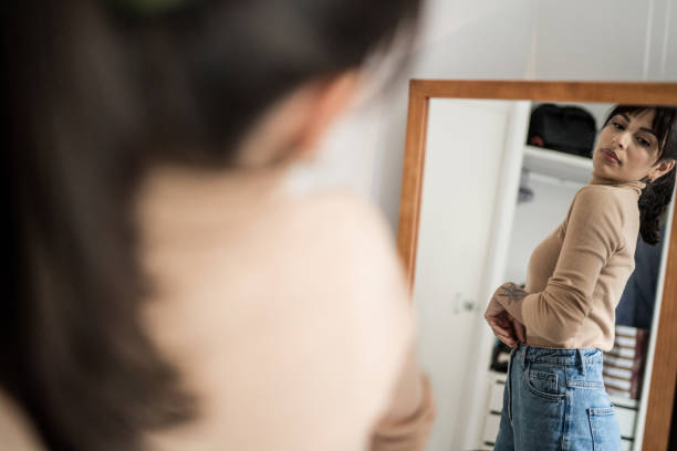 junge frau zieht sich zu hause vor einem spiegel an - women choosing choice clothing stock-fotos und bilder