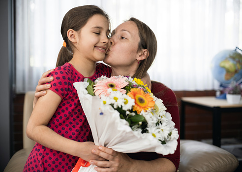 Children Surprising Mother On Mother's day With Bouquet And Greeting Card