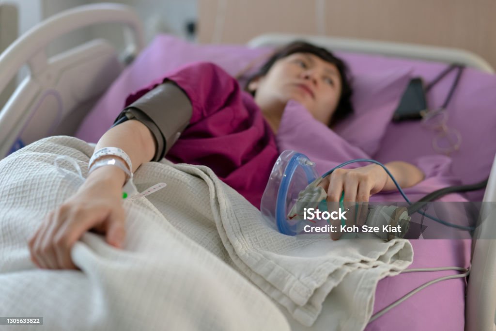 Pregnant asian female patient laying in bed preparing for childbirth with the help of laughing gas Miscarriage Stock Photo