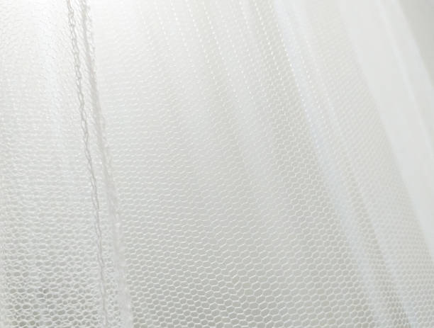 折り目付きの白い蚊の網の生地をクローズアップ。波状シフォンの背景。くしゃくしゃの白い布の素材の質感。パターンとデザインのための抽象的な白いネットファブリックパターン。 - gauze bandage textured white ストックフォトと画像