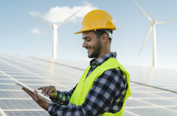 istock Young engineer watching on digital tablet the new green plan for alternative energy with wind turbine and solar panel - Innovation and green power concept 1305636538