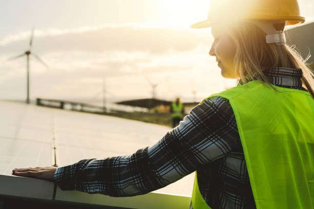 jeune ingénieur travaillant pour l’énergie alternative avec l’éolienne et le panneau solaire - innovation et concept d’énergie verte - working windmill photos et images de collection