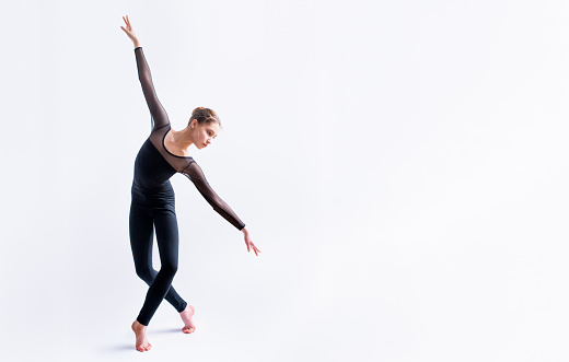 ballet girl in a black tight-fitting suit dances on white background with modern contemporary choreography