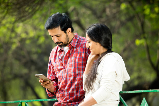 istock Happy couple using phone at park 1305637888