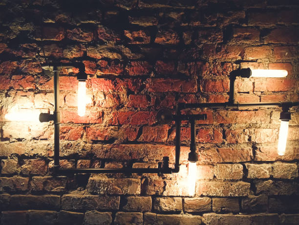 istock Interior design of vintage wall. Rustic design, brick wall with light bulbs and pipes, low lit bar interior 1305639949