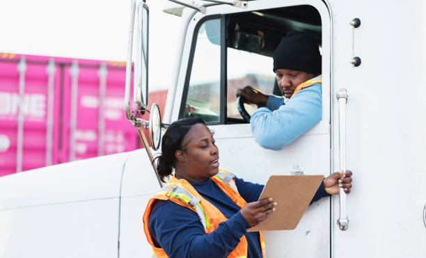 istock Truck driver, female dock worker looking at clipboard 1305640666