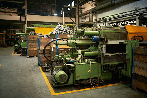 Metal working machinery and bins filled with manufactured castings on foundry floor.