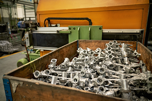 Large bin filled with casting parts manufactured in metal working foundry.