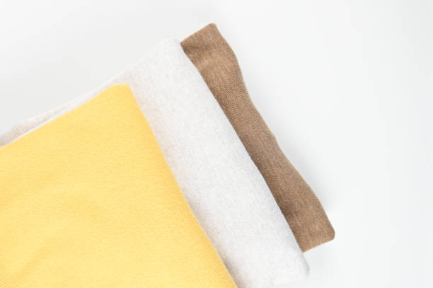 istock Cropped view of stack of folded colorful clothes isolated on white, space for text. Brown, grey and yellow color tone 1305642518