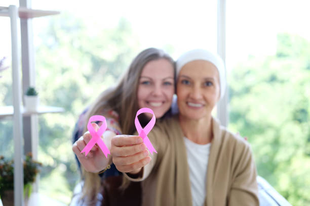 kaukaska córka i starsza matka w białej chustce trzyma świadomość różowa wstążka wspólnego raka jest symbolem różnych działań kampanii dla pacjentów z rakiem piersi. skoncentruj się na dłoni kobiet - pink ribbon alertness breast cancer awareness zdjęcia i obrazy z banku zdjęć