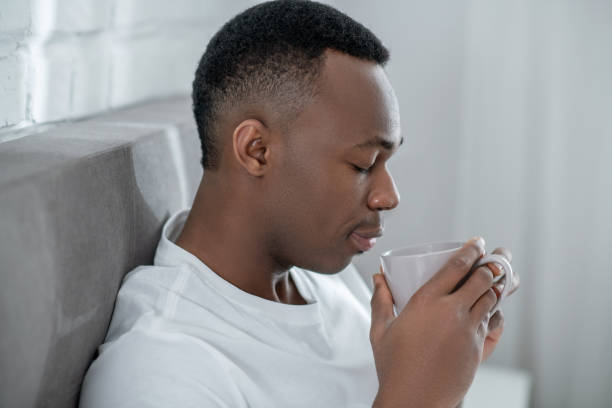 istock A young man in white tshirt feeling comfortable and having coffee in bed 1305646186