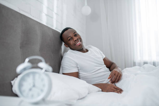 istock A young man in white tshirt lying in bed and looking sleepy 1305646192