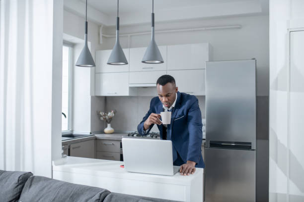 istock Elegant dark-skinned man reading something on laptop and looking excited 1305646244
