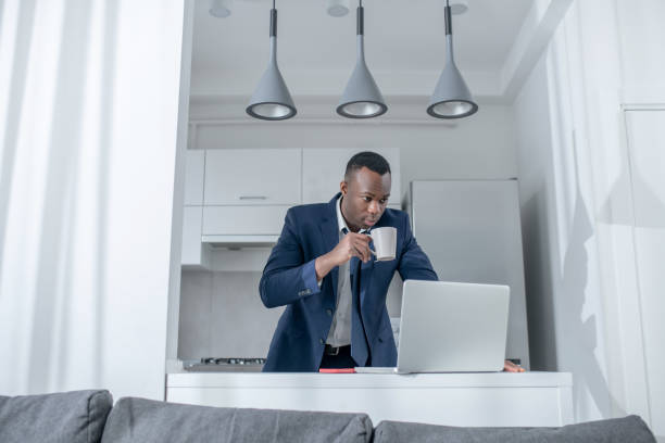 istock Elegant dark-skinned man reading something on laptop and looking excited 1305646250