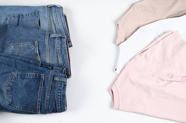 istock Cropped view of pink and white t-shirts, blue jeans. Free space for text, mockup. Basic wardrobe concept. Flat lay casual outfit. 1305647183
