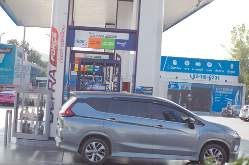 Car at PTT gasoline station in Bangkok Ladprao at afternoon sunshine. In background is a service garage. Scene is on Wanghin Road