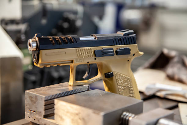 A modern pistol with a beige grip on a work table in a workshop. Service maintenance of weapons. Pistol repair.