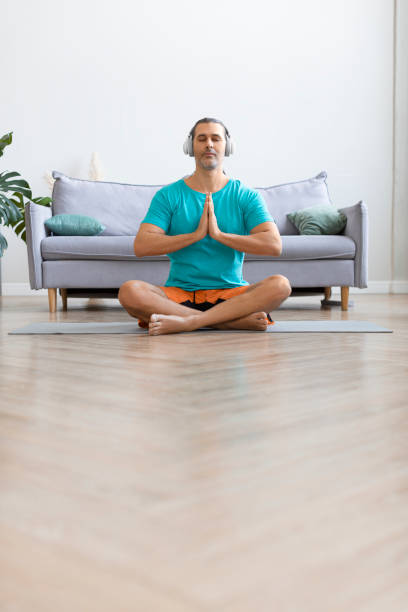 istock Workout at home. Middle aged man meditating while doing yoga. Vertical photo 1305650492